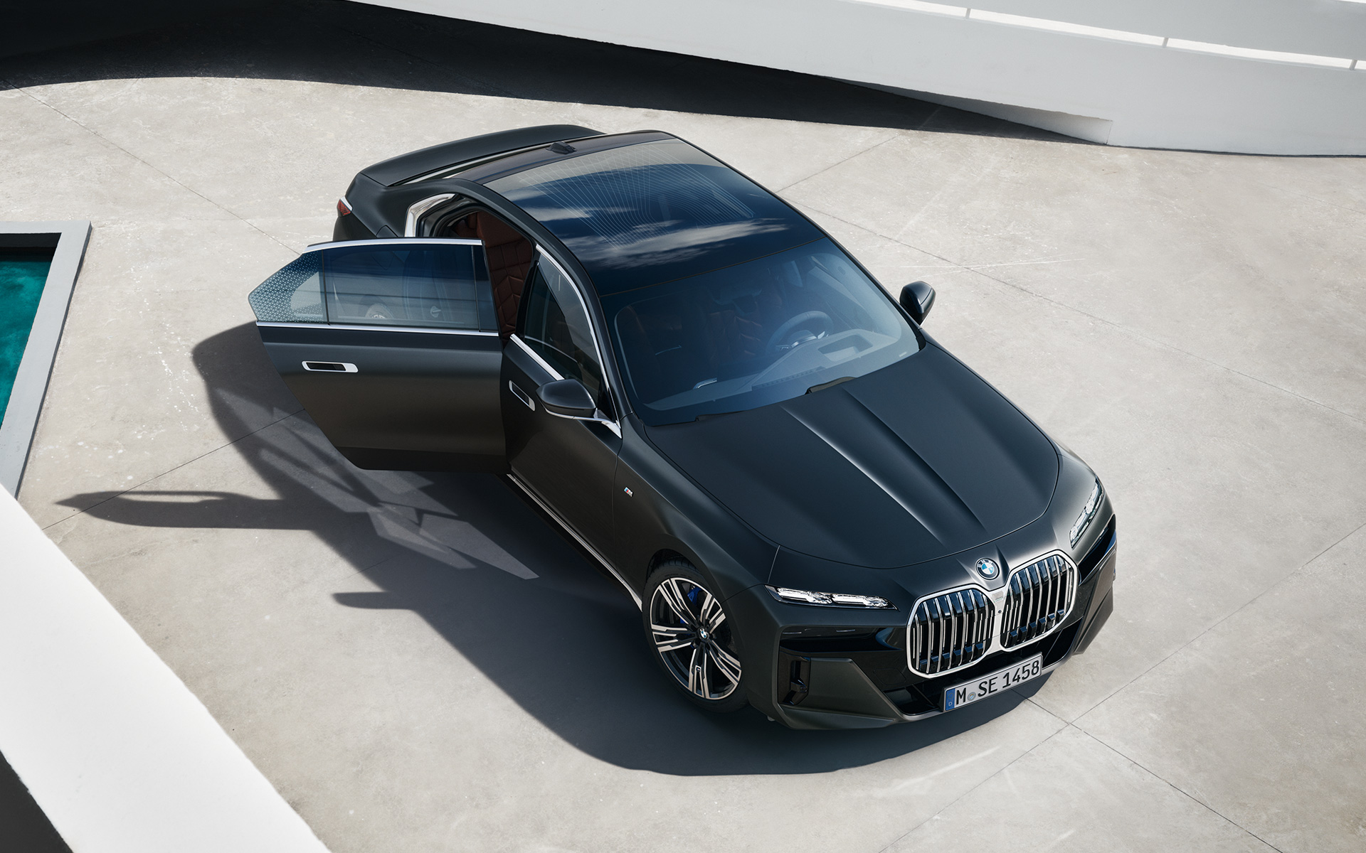 BMW 7 серии Седан G70 ICE 740i с пакетом M Sport в цвете Frozen Deep grey metallic, вид с высоты птичьего полета с открытой пассажирской дверью