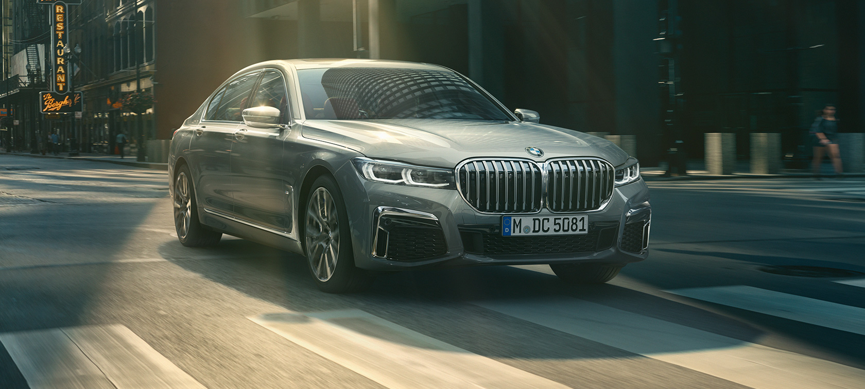 BMW M760Li xDrive Седан G11 G12 2019 в цвете Frozen Dark Silver metallic, вид на три четверти сзади в городских условиях.